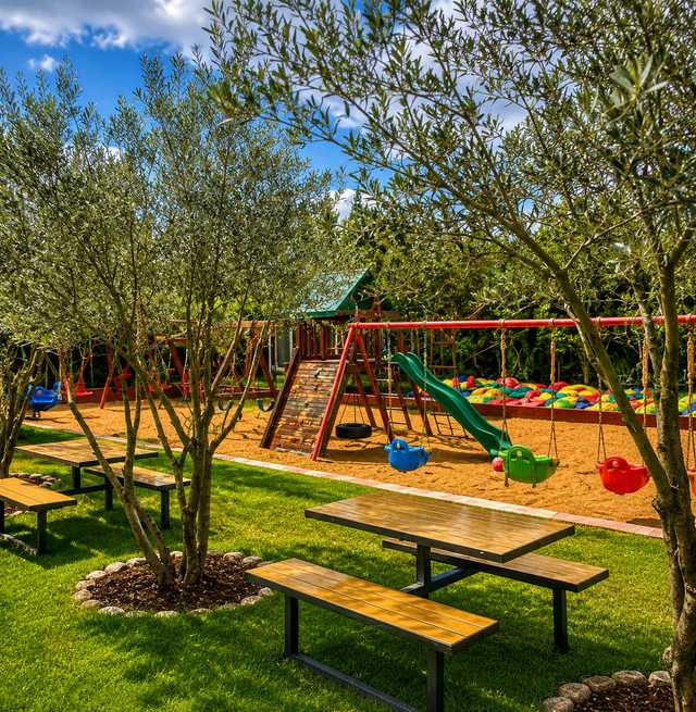 Garden play area with a wooden playground, swings, a ping-pong table and shaded outdoor seating